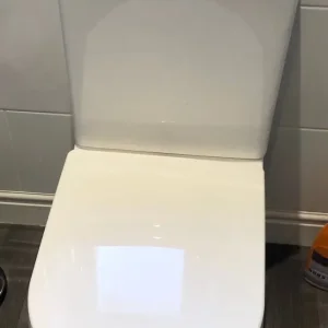 Two white toilets and a white hand basin - Image 2