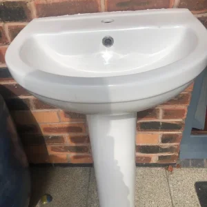 Two white toilets and a white hand basin - Image 5