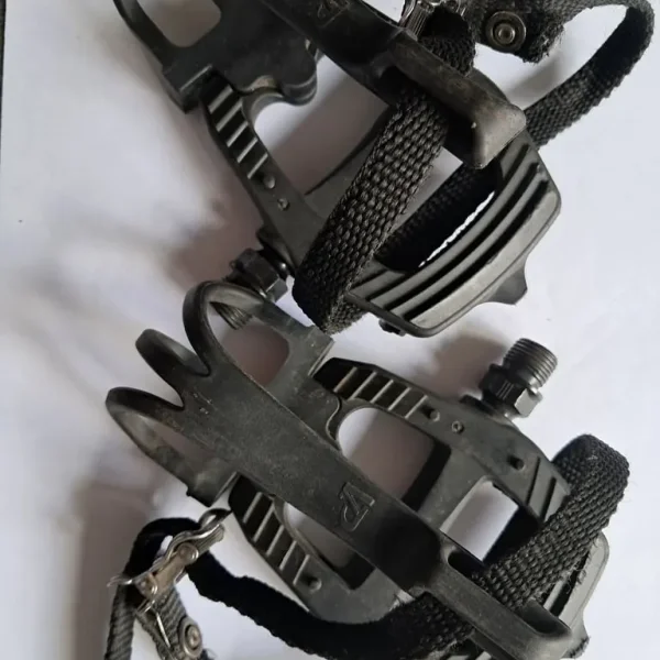 Pair of black bike pedals, toe caged with straps