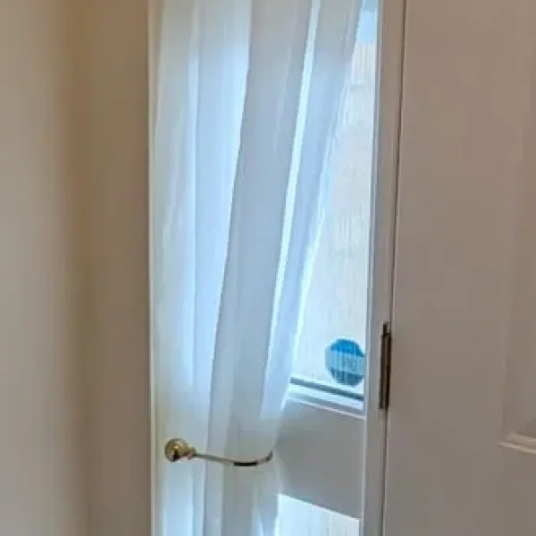 Pair of cream door curtains with gold rails and tie backs