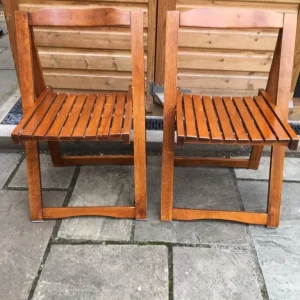 Two identical wooden folding garden chairs with latted seats