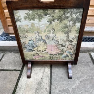 An old oak framed firescreen with colourful glass fronted embroidery.