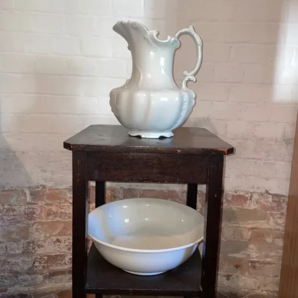 Antique white ceramic wash bowl and ewer (jug) on wooden stand